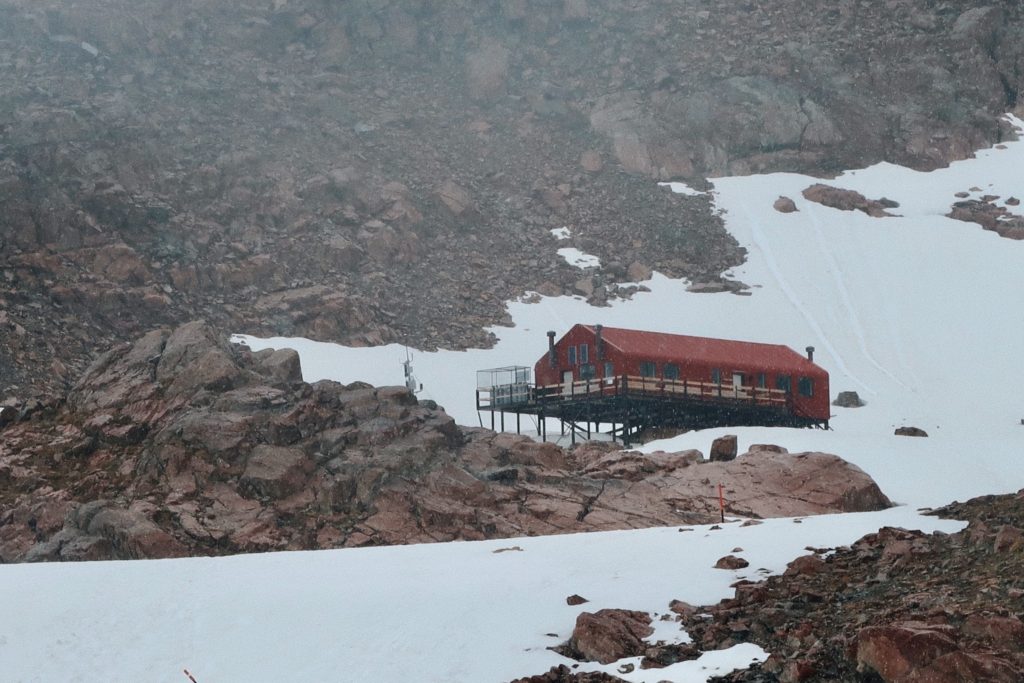 a red hut surrounded by snow and mountain