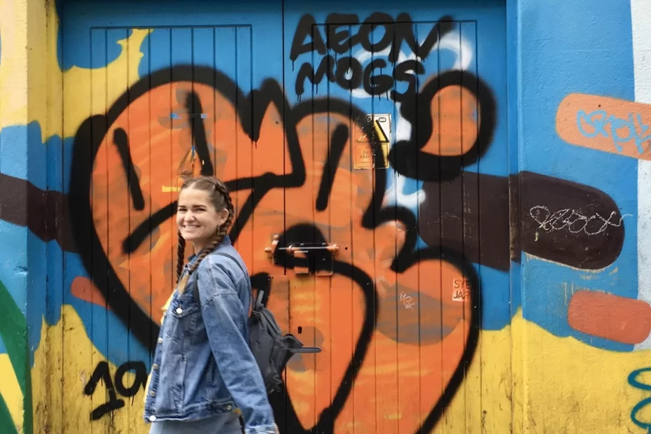 Niki walks in front of a graffitied wall in Dublin