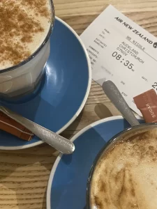 two lattes in mugs with a boarding pass in the background