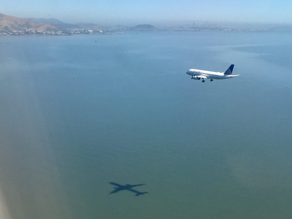 how to pack light: airplane flies over a large body of water in san francisco