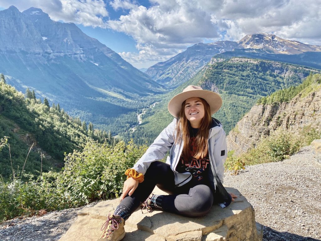 glacier national park itinerary: niki poses in front of mountains and valleys