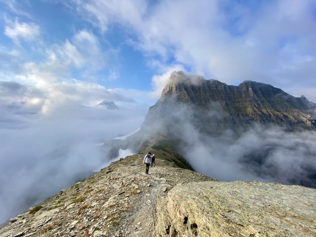 glacier national park itinerary: ben and niki's family walk the foggy ridge line of a mountain