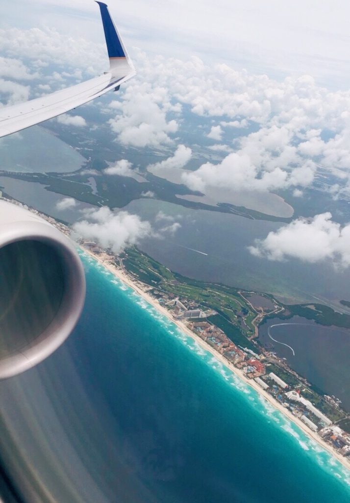 how to ace your flight attendant interview: airplane wing and engine flying over a beautiful beach