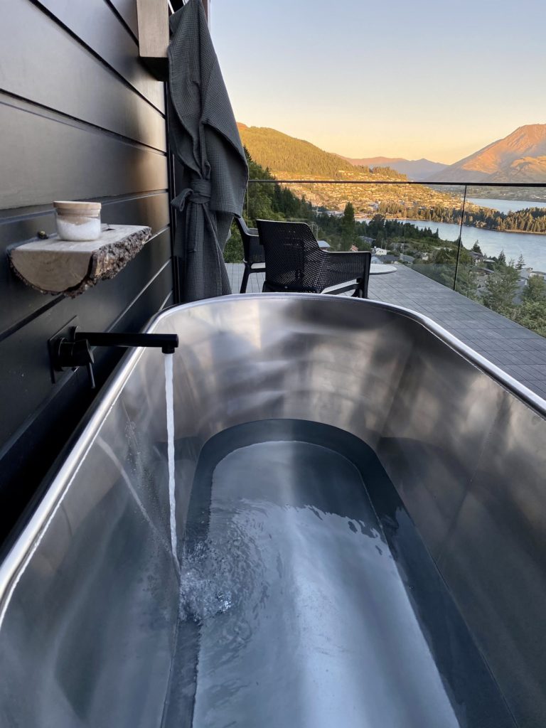 kamana lakehouse outdoor bathtub and view of queenstown at golden hour