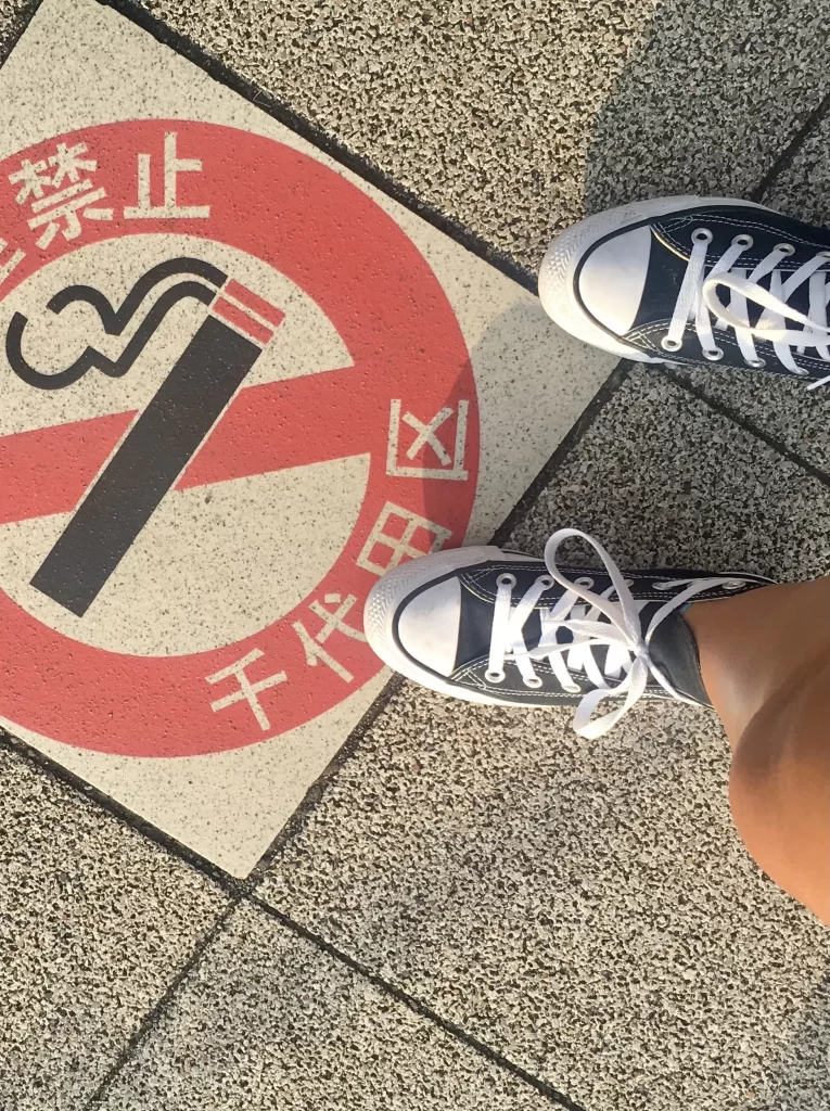 a set of black converse stands on a no smoking sign in japanese