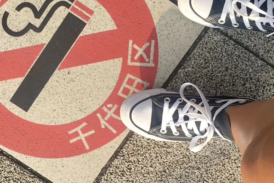 a set of black converse stands on a no smoking sign in japanese