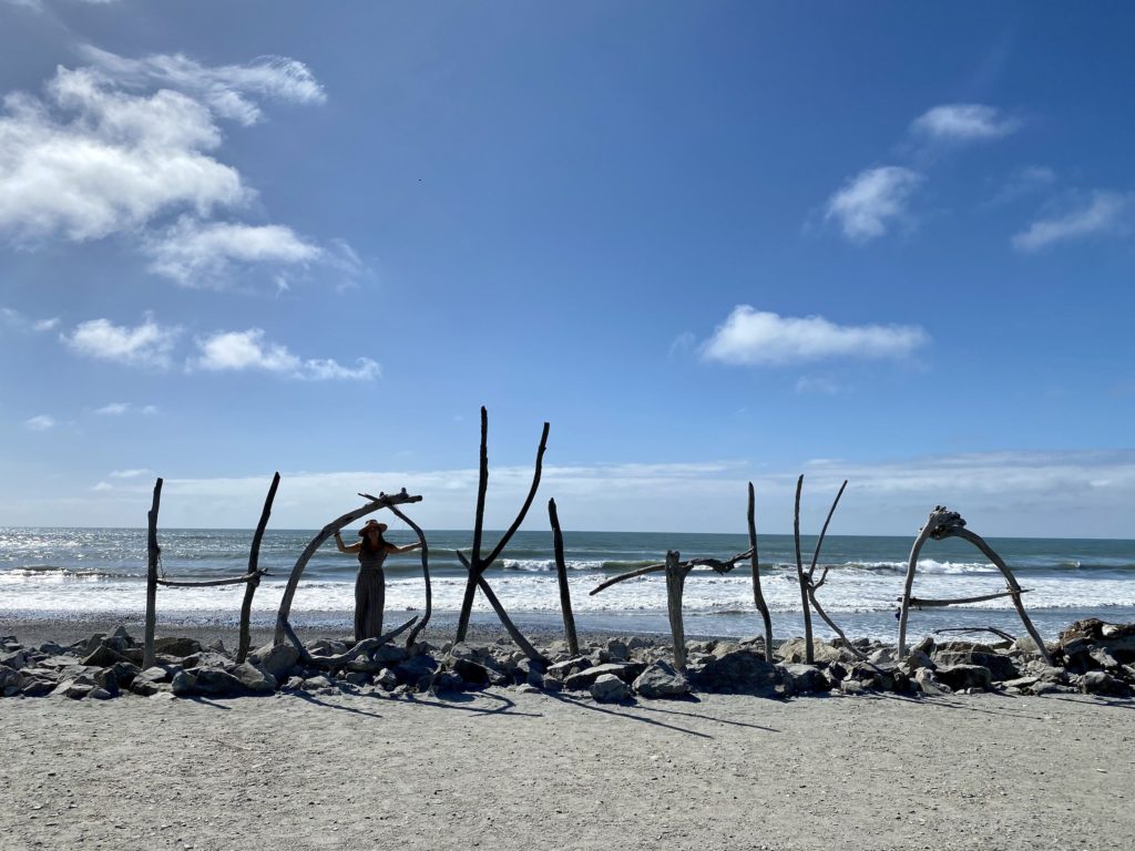 west coast day 3: niki stands near hokitika beach sign