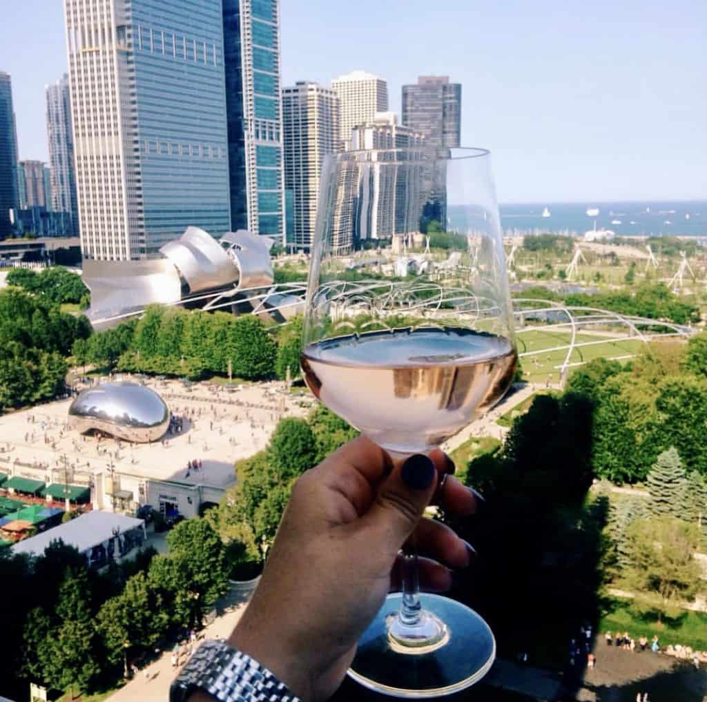 chicago summer activities: glass of wine and view of millennium park from a rooftop bar