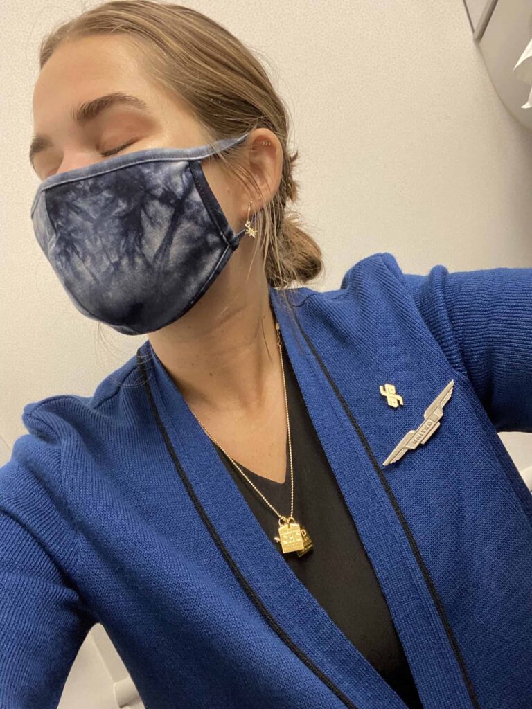 pandemic travel: niki wears a face mask in her flight attendant uniform