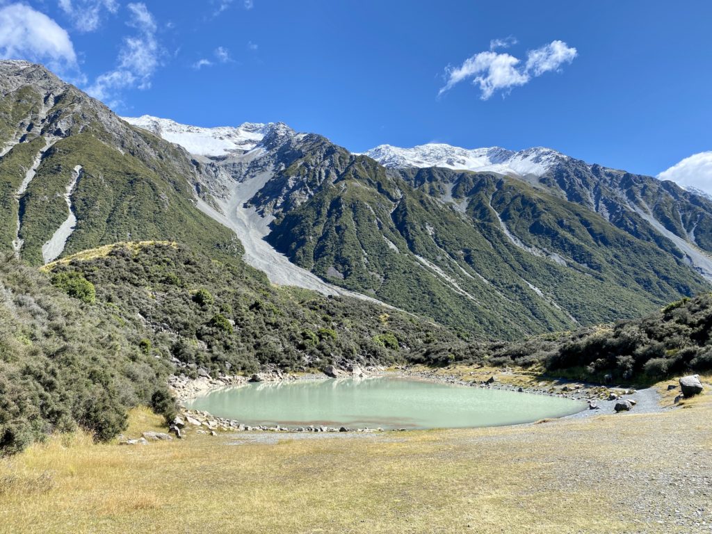 blue lakes and tasman glacier: mountains behind a greenish lake