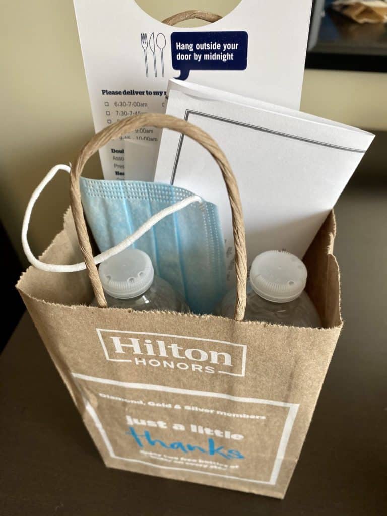 water bottles and a reusable mask given by hilton hotel in a goodie bag