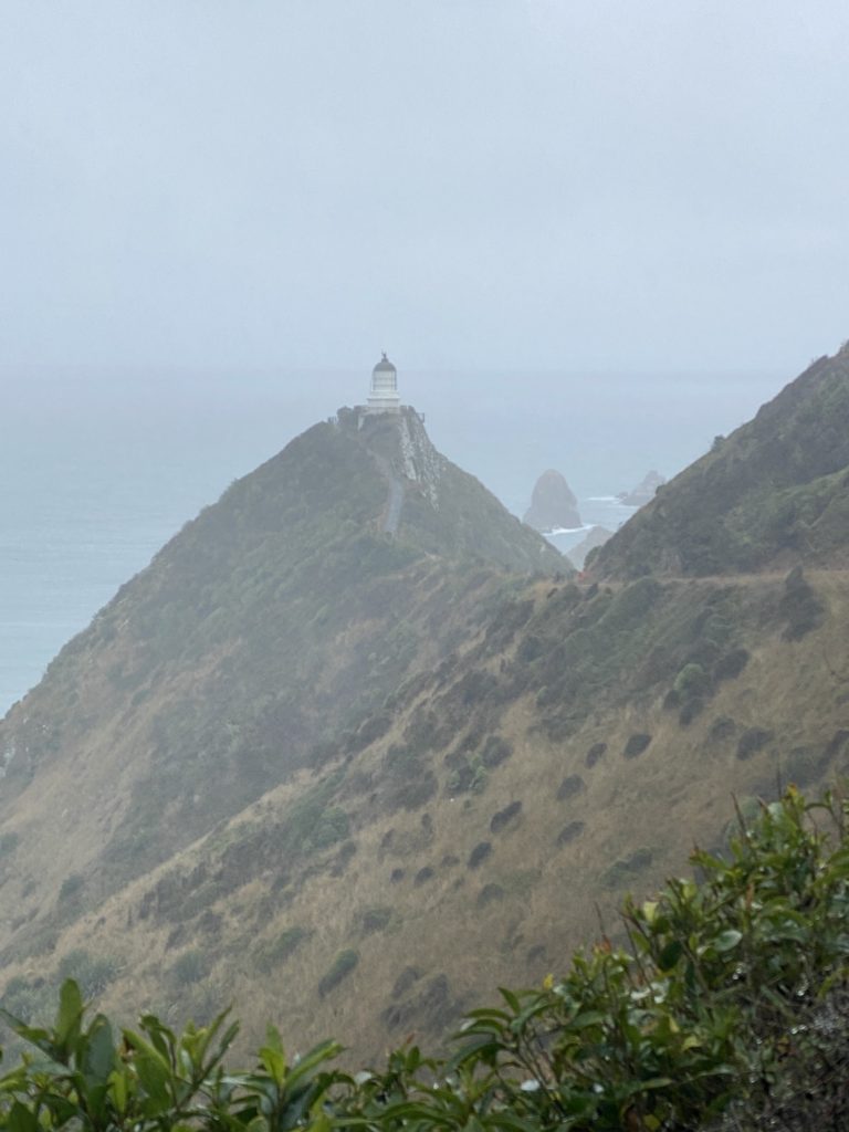 Nugget Point Lighthouse in the distance obscured by fog