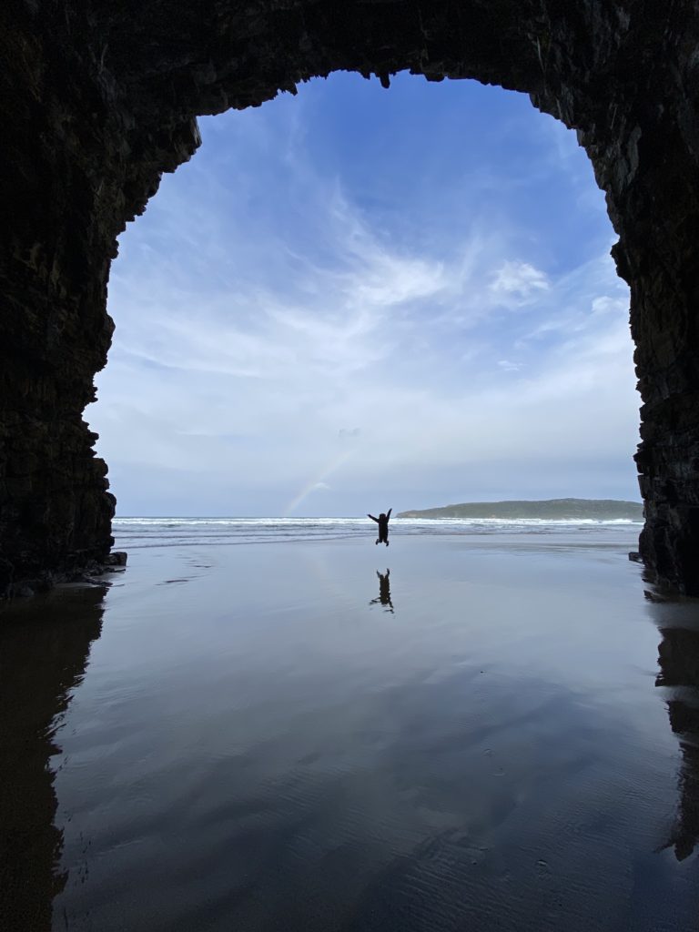 Catlins road trip itinerary: Niki jumps by the beach at Cathedral Caves