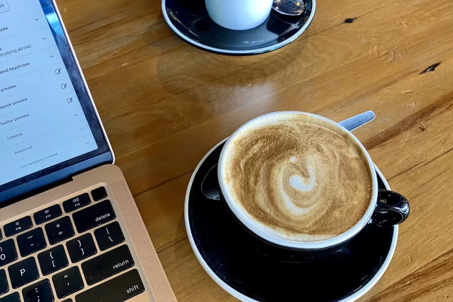 How to plan a trip: two coffees and a rose gold laptop at a cafe in New Zealand