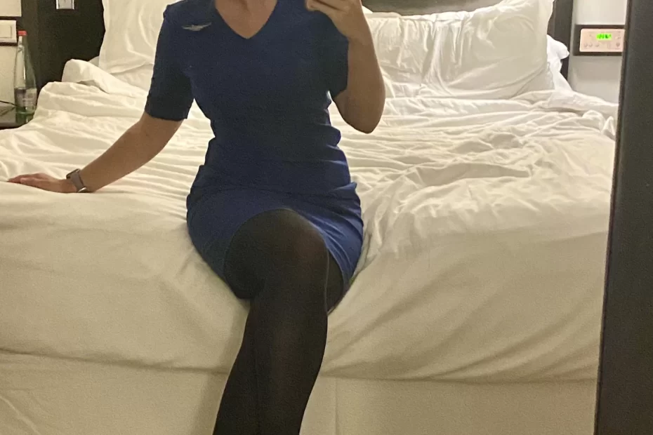 Niki in her flight attendant uniform sitting on a hotel bed in Tel Aviv, Israel