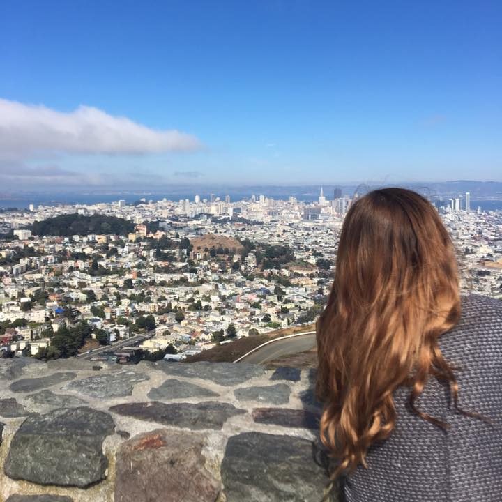 San Francisco travel guide: Niki stands in front of a view of San Francisco from Twin Peaks