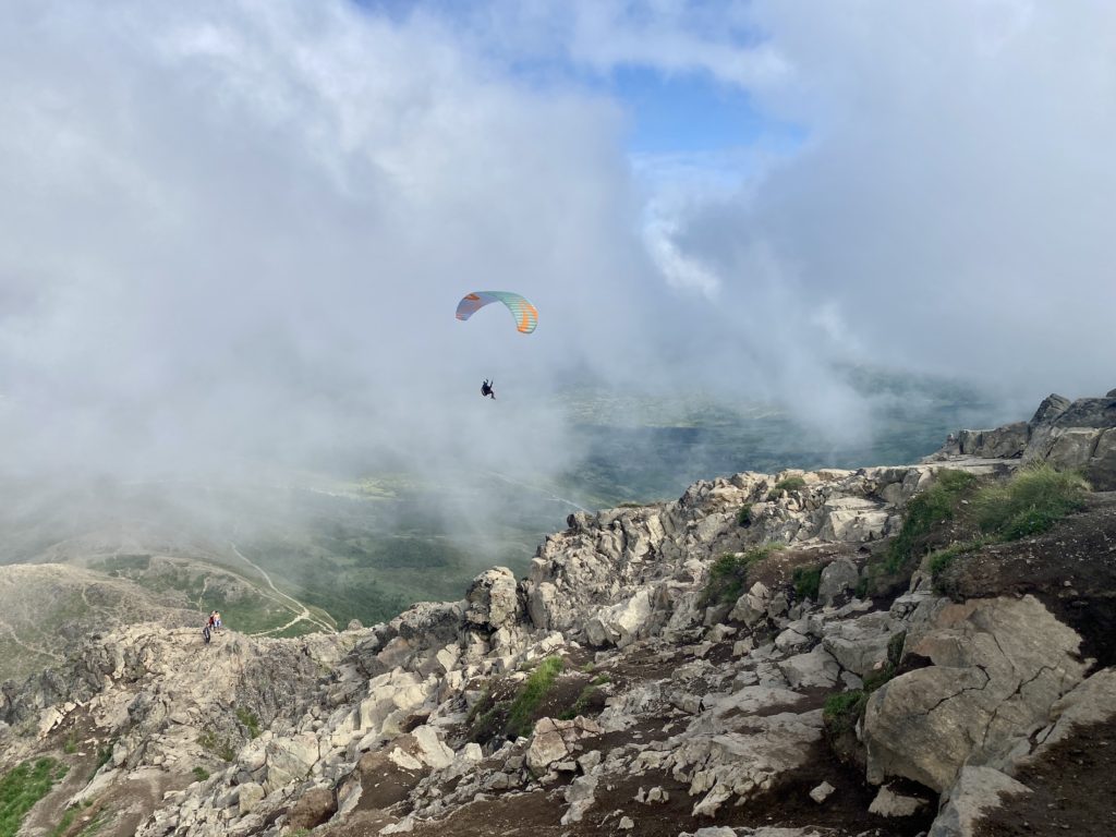 Someone paragliding off the top of the summit into clouds