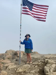 Niki at the peak of Flattop Mountain in front of an American flag