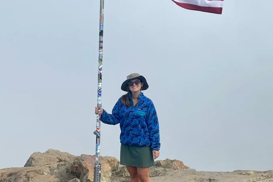 Niki at the peak of Flattop Mountain in front of an American flag