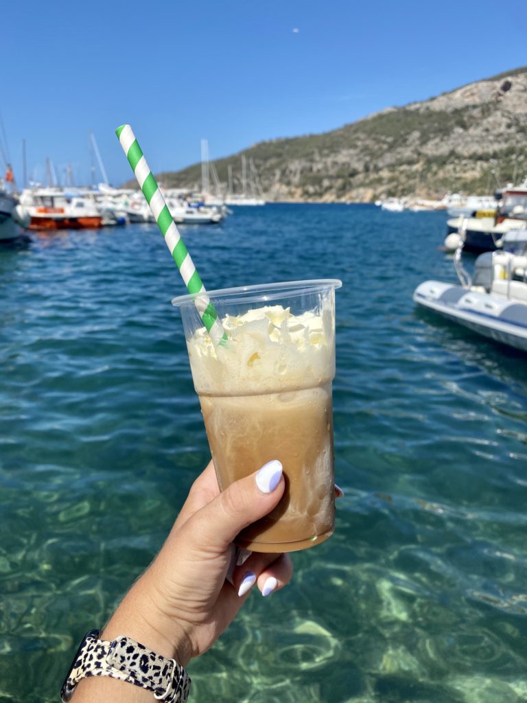 Iced coffee with whipped cream in front of blue water in Vis island, Croatia