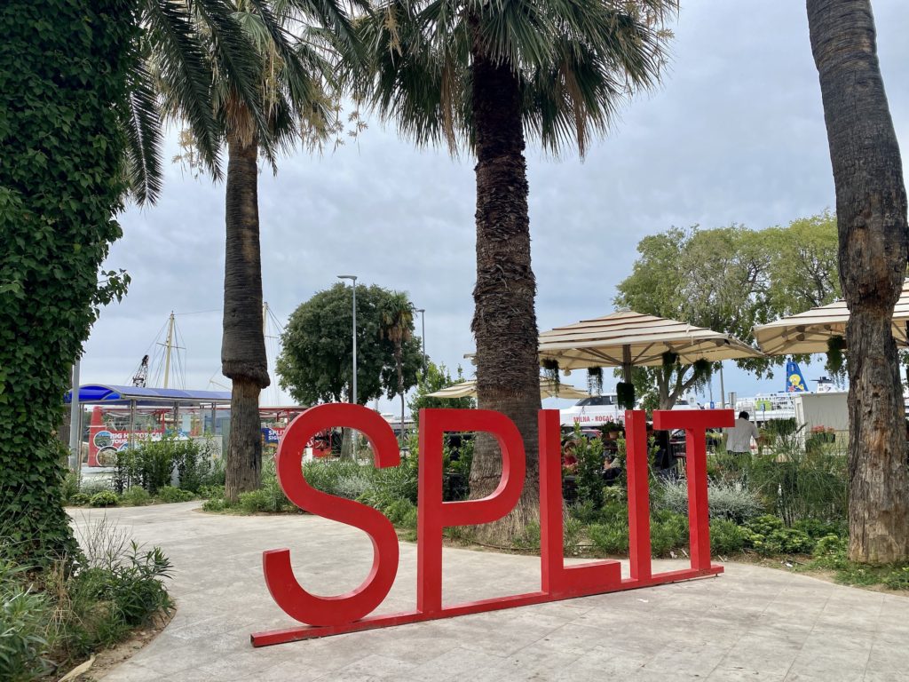 Split travel guide: red Split sign with palm trees in the background