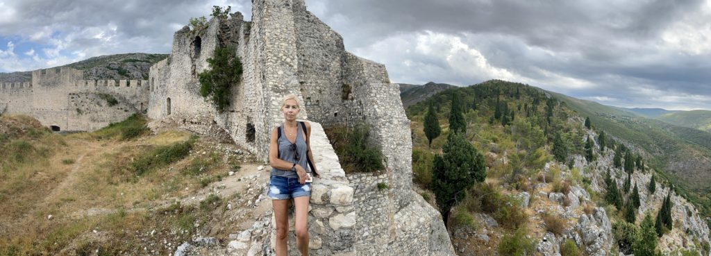 Lucy sits on the ruined edge of Old Town Fortress, Blagaj, Bosnia & Herzegovina