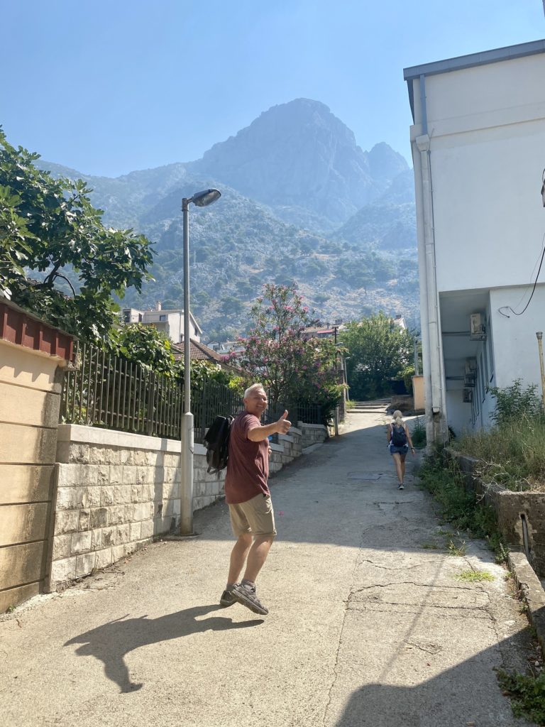 Kotor travel guide: Les gives a thumbs up in front of mountains, Kotor, Montenegro