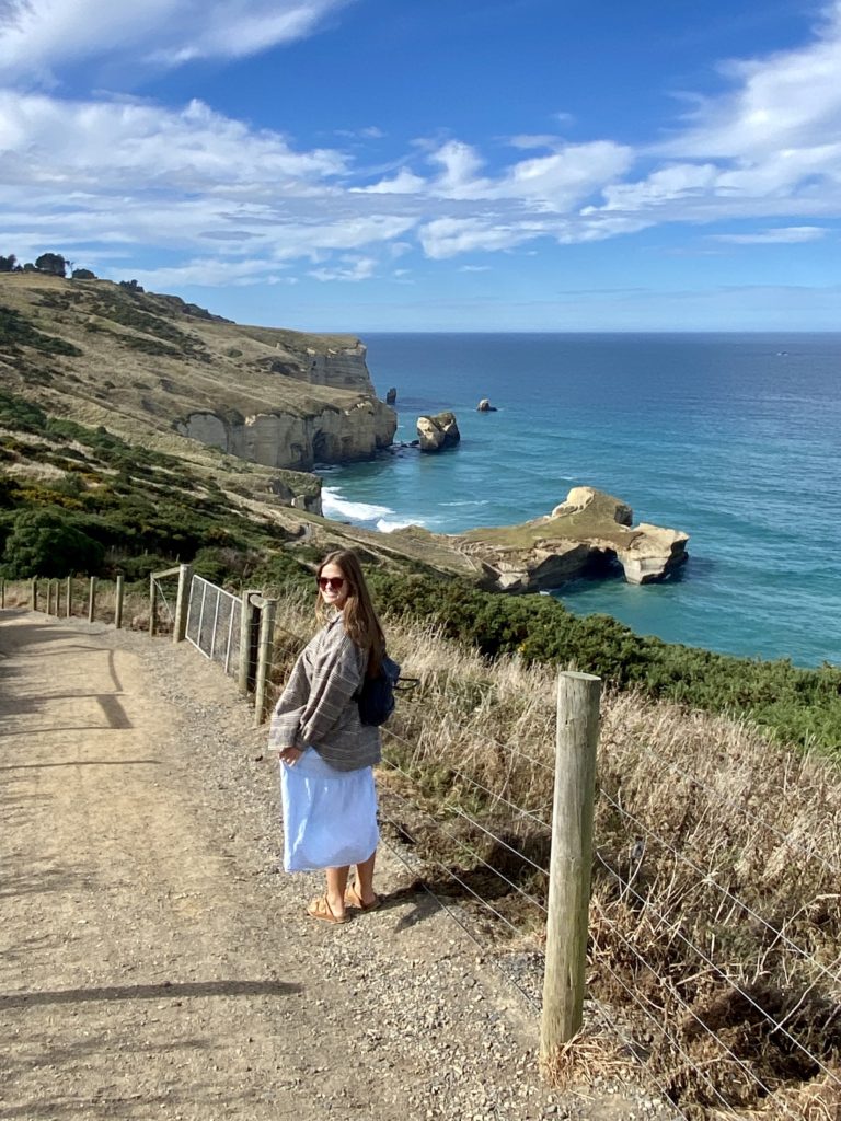 South Island New Zealand road trip: Niki stands in front of the ocean, Dunedin, New Zealand