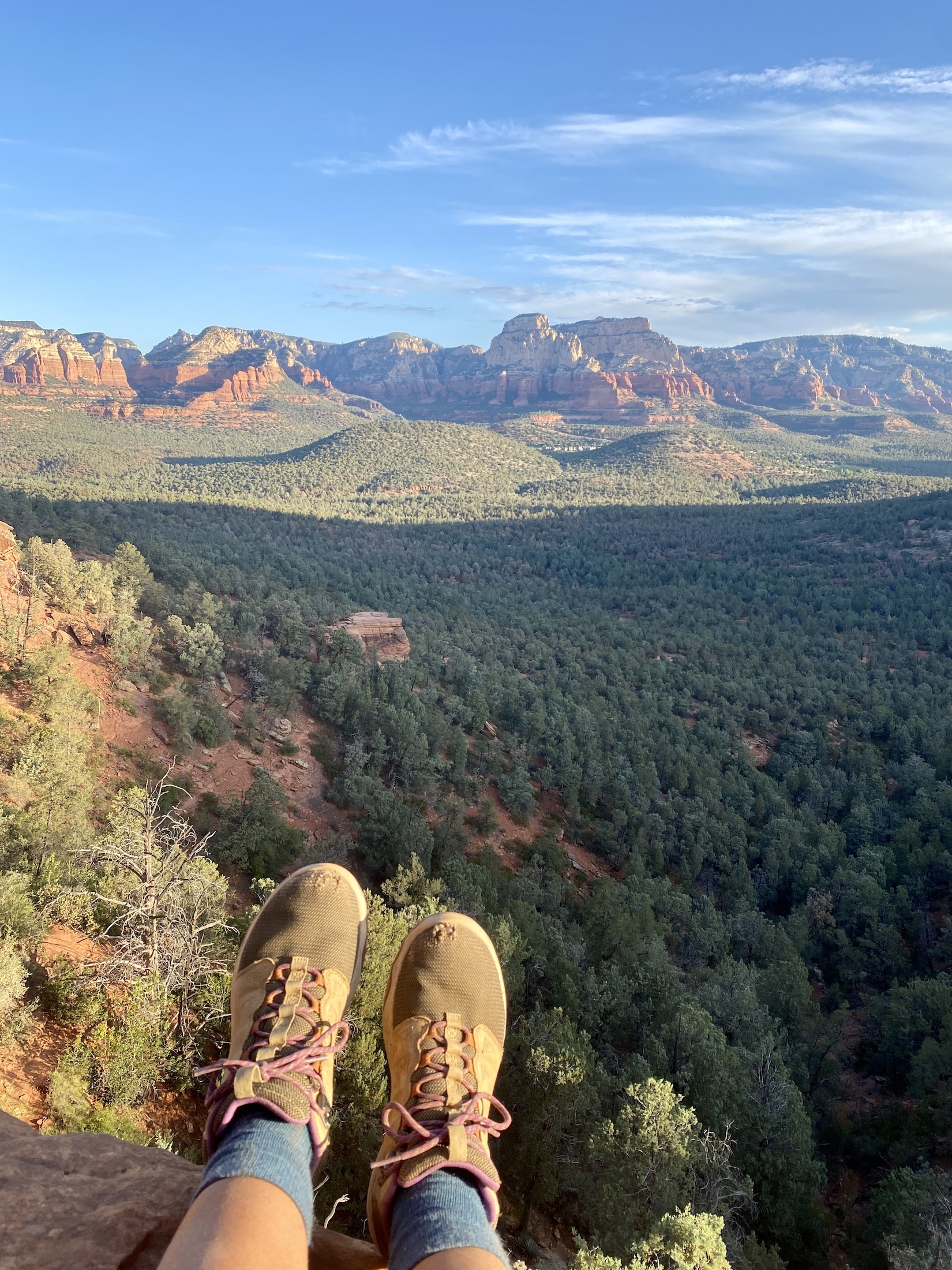 Hiking boots dangling in front of a view of mountains and valley in Sedona, Arizona