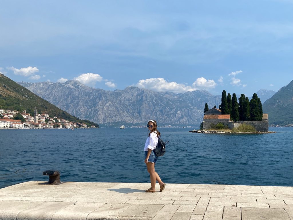 Niki stands in front of islands in Perast, Montenegro