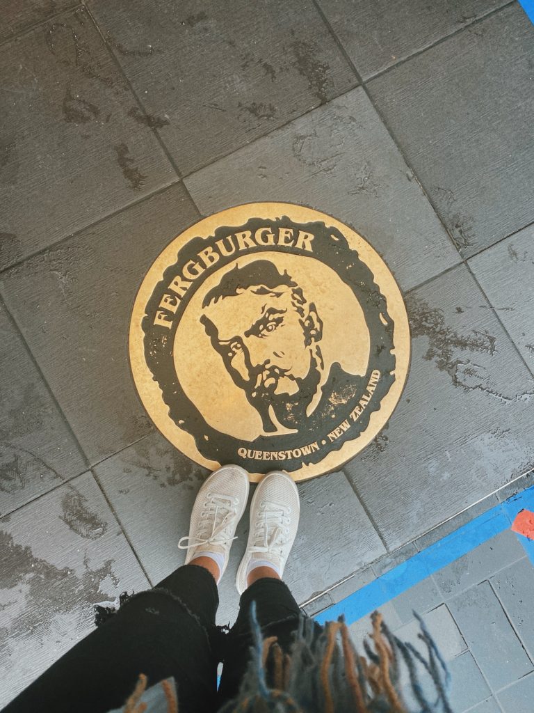 One Second Everyday in 2021: Niki's shoes on top of a sign for Fergburger in Queenstown, New Zealand