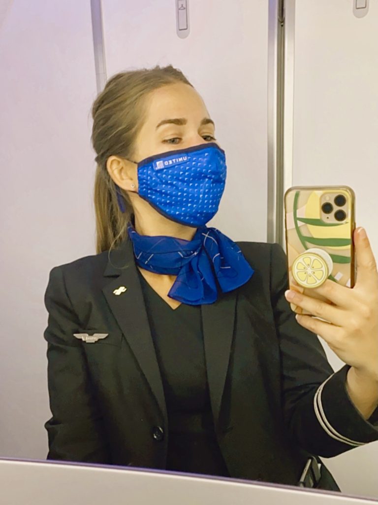 Niki takes a selfie in an airplane lavatory in her flight attendant uniform