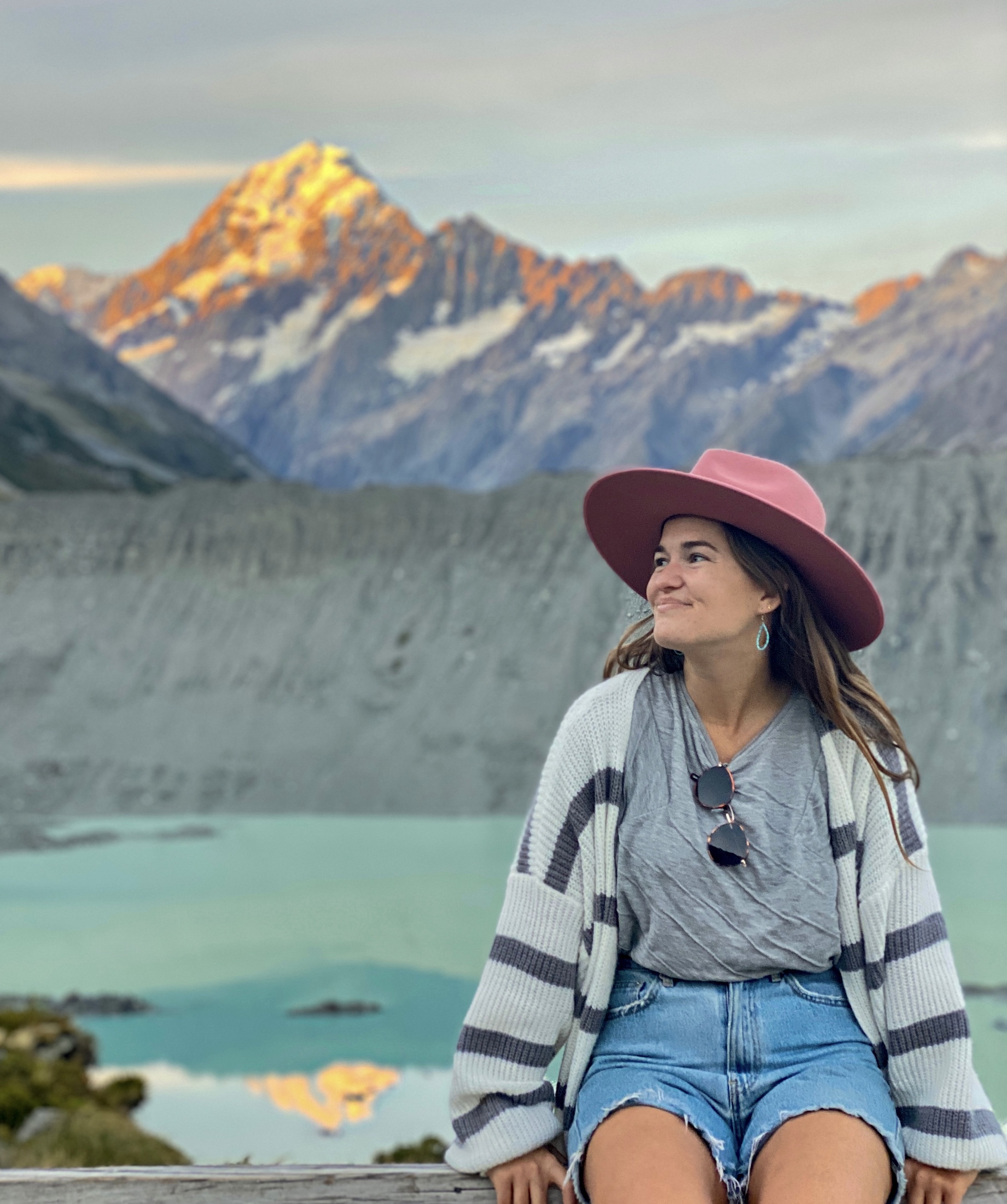 about me: niki sits in front of aoraki/mt cook, aoraki/mt cook national park, south island, new zealand