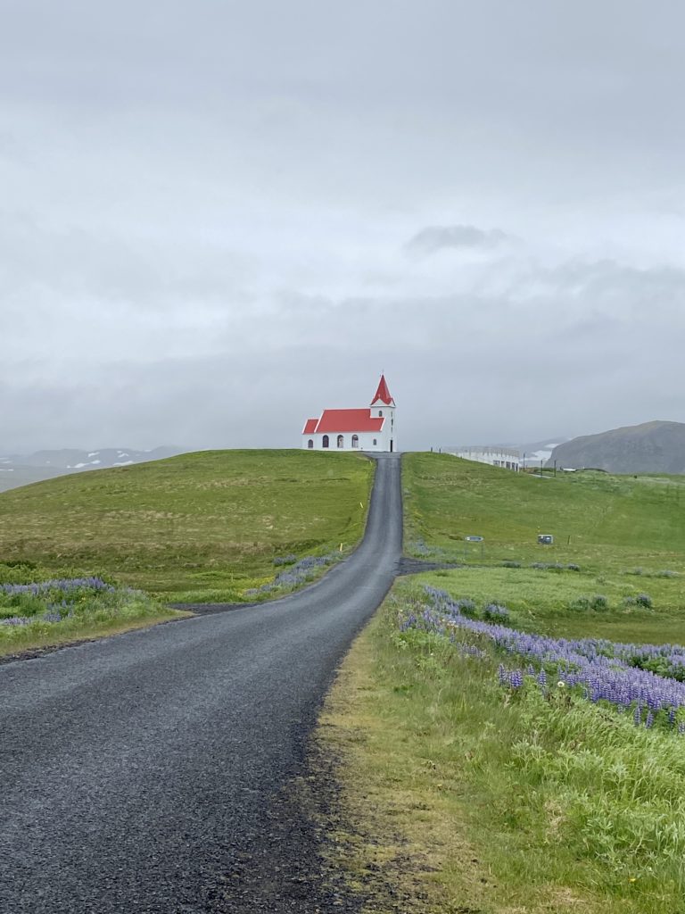 Paved road to a red church