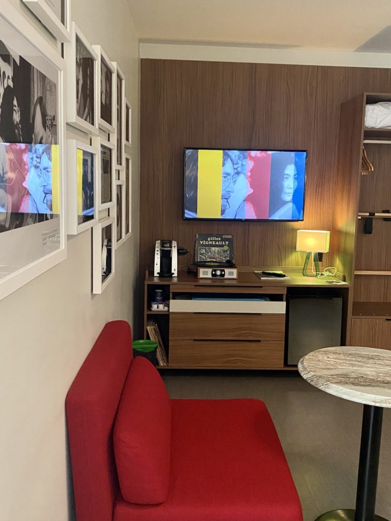 Hotel Uville Montreal room: TV, mini fridge, coffee machine, record player, and red couch