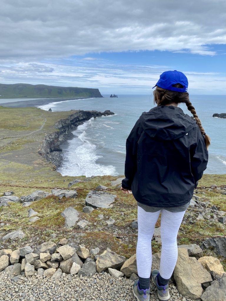 Niki stands in front of the ocean at Dyrholaey Nature Reserve, Iceland
