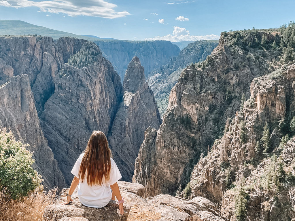 Things to do in Black Canyon of the Gunnison National Park: Niki sits in front of an overlook on South Rim Road, Colorado