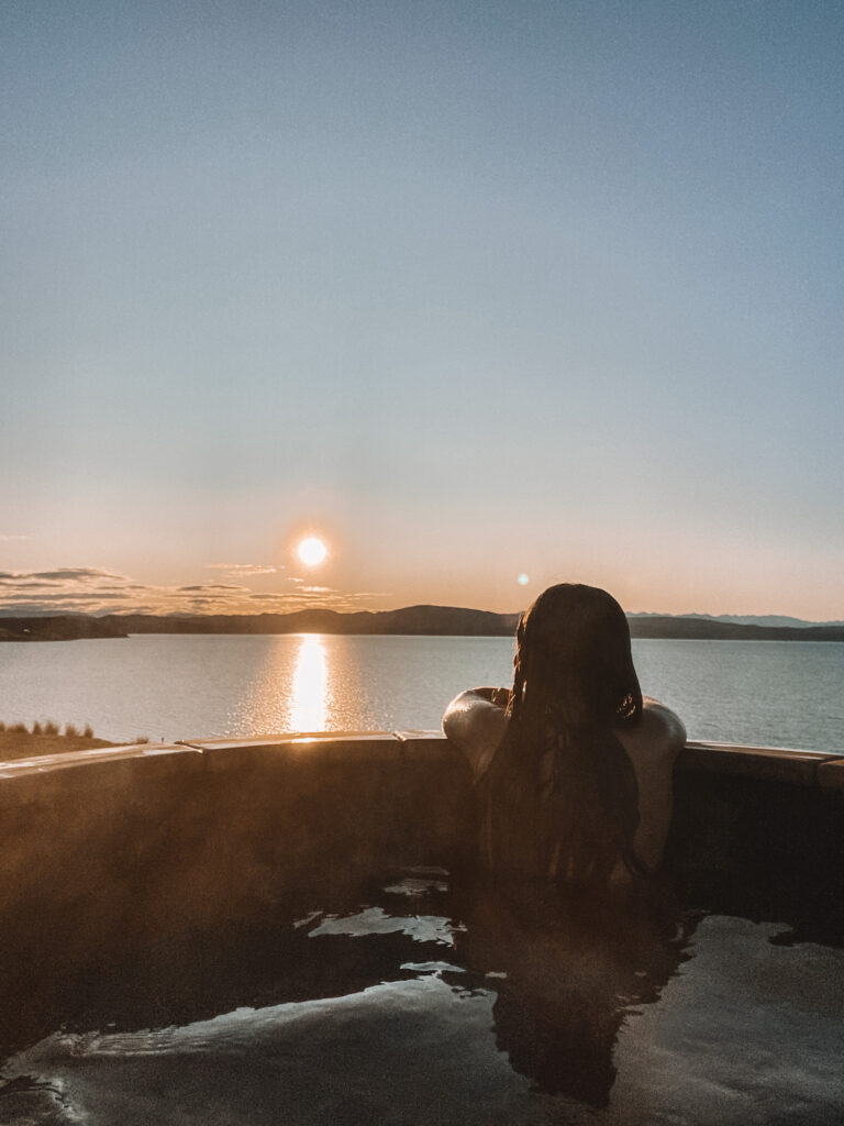 Niki sits in a hot tub at sunrise over Lake Pukaki, South Island, New Zealand
