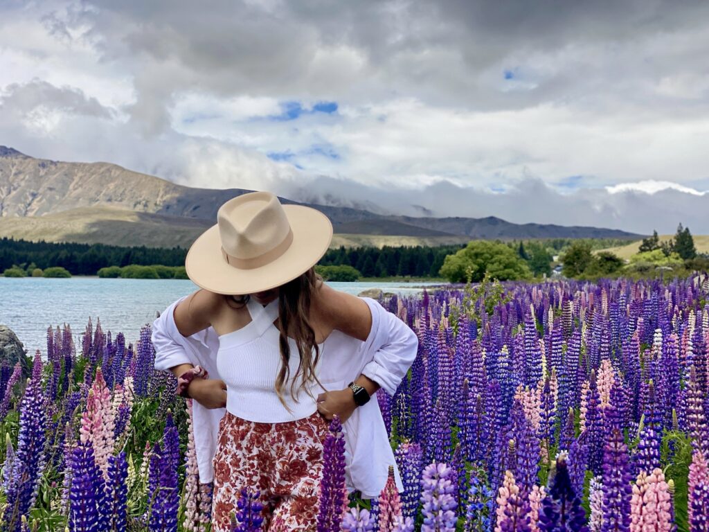 Christchurch to Queenstown road trip itinerary: Niki stands in a field of lupins near Lake Tekapo, New Zealand