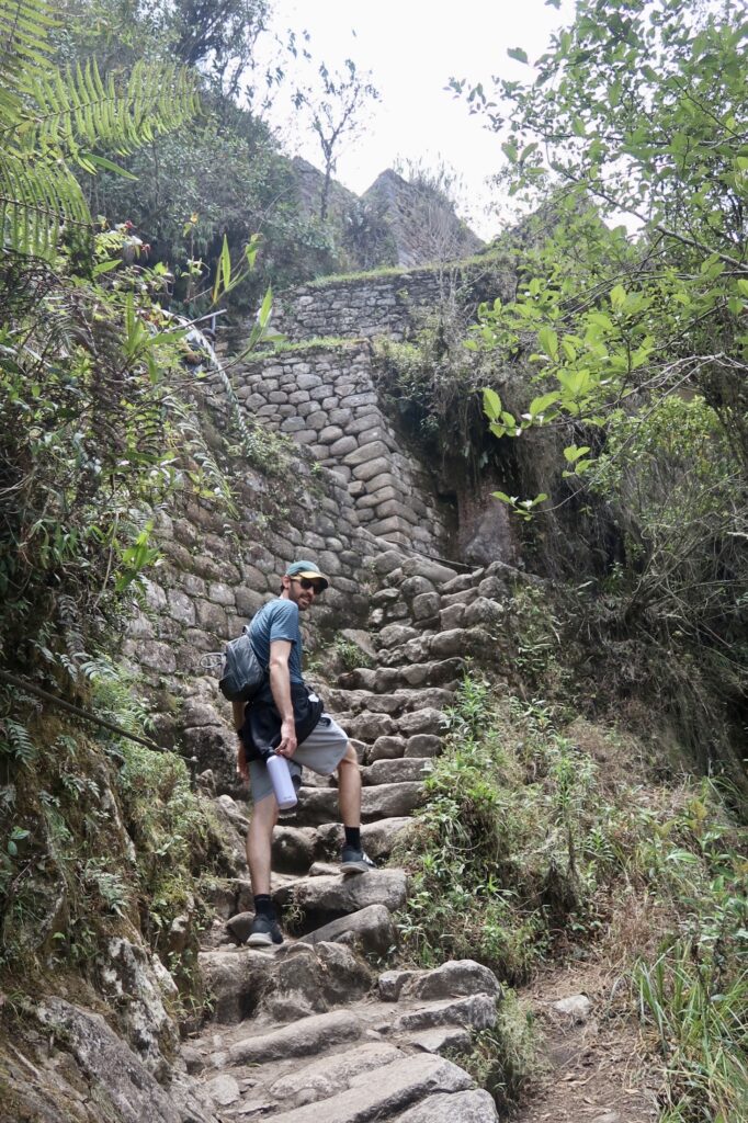 Ben climbs up stairs while hiking Huayna Picchu, Peru
