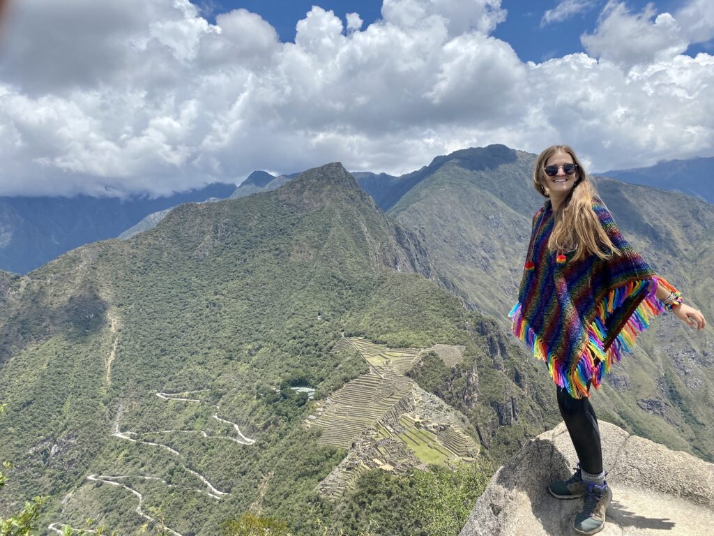 Niki in a rainbow poncho with a view of Machu Picchu in the background, Peru