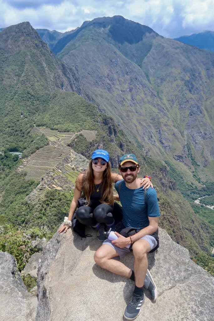 Niki and Ben at the summit of Huayna Picchu, with a view of Machu Picchu archeological site in the background, Peru