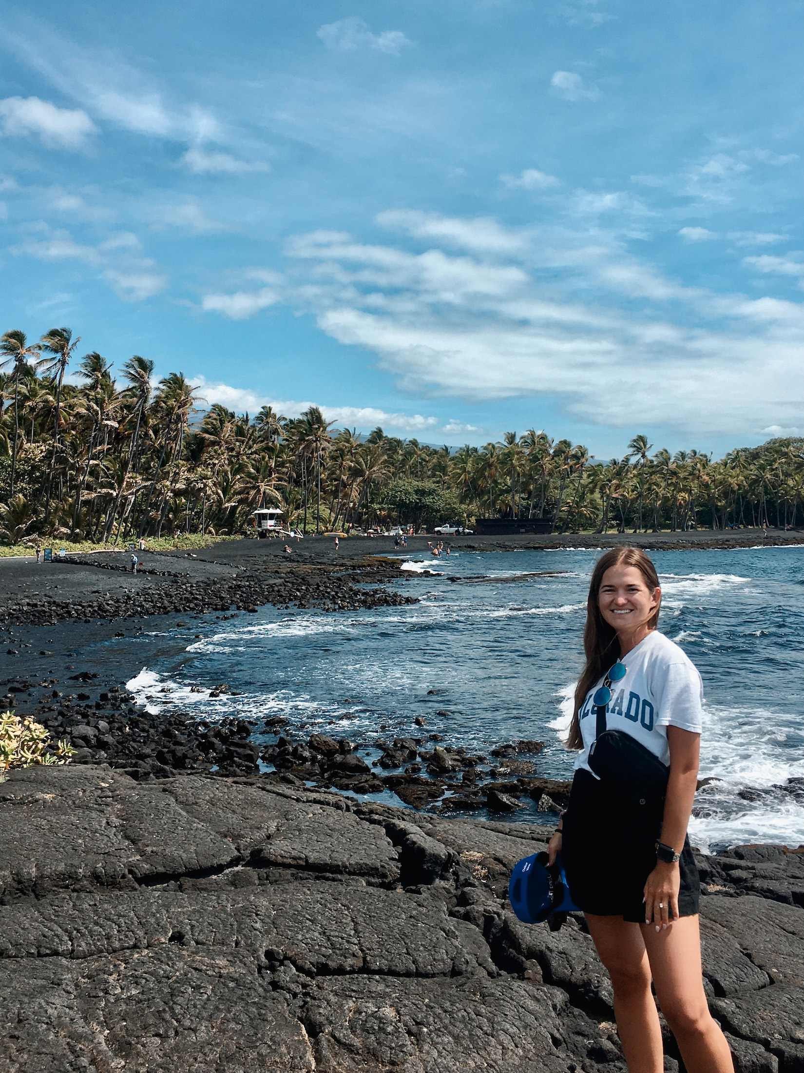 Niki stands in front of a black sand beach, Big Island, Hawaii, USA