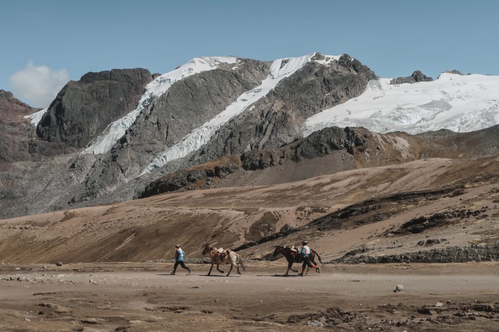 Local men running downhill with horses, Rainbow Mountain hike, Cusco, Peru