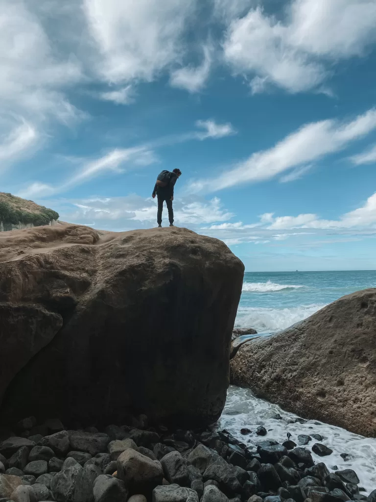 Ben stands on a rock, Tunnel Beach, Dunedin, Otago, New Zealand