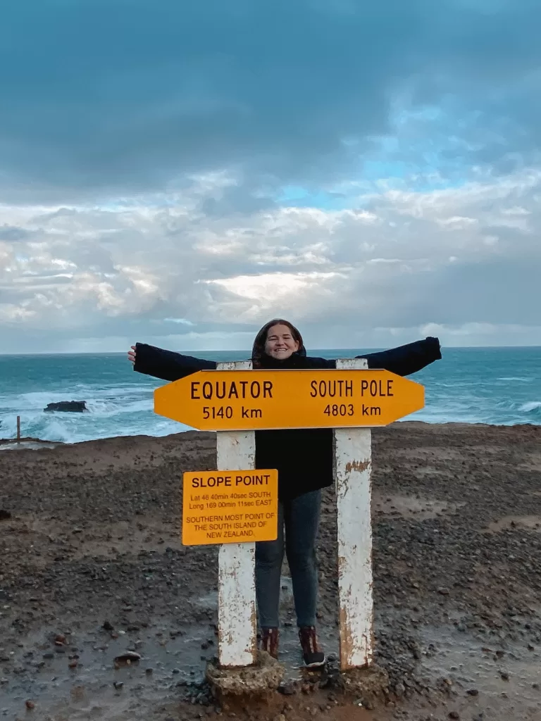 Best day hikes South Island New Zealand: Niki stands at Slope Point, southernmost point of the South Island, the Catlins, New Zealand