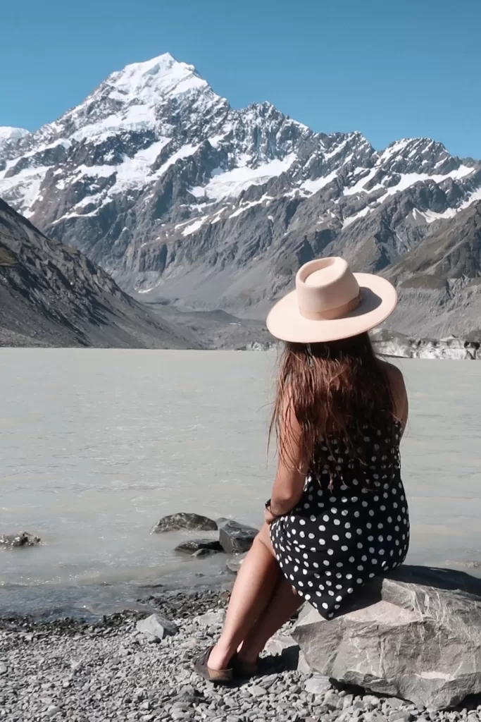Best day hikes South Island New Zealand: Niki sits in front of Hooker Lake and Aoraki Mount Cook, Hooker Valley Track, Aoraki Mount Cook National Park