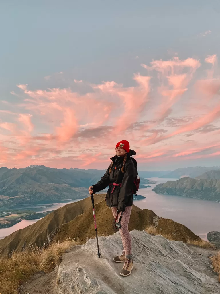 Best day hikes South Island New Zealand: Niki stands on Roys Peak Track at sunset, Wanaka, Otago