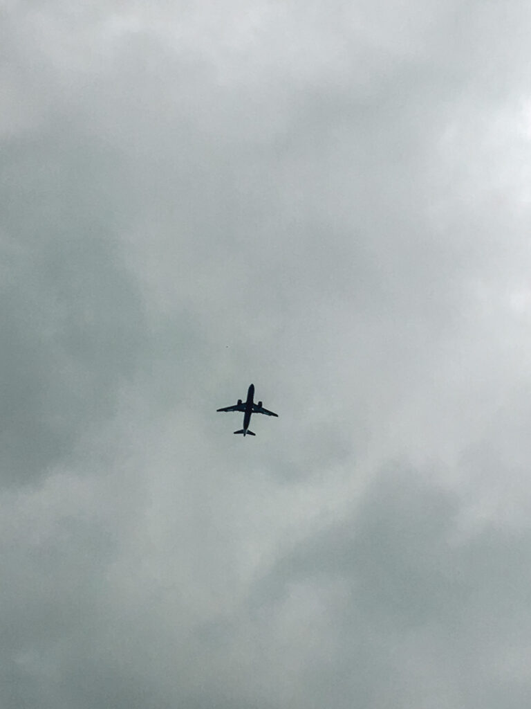 Flying captions: Airplane silhouette on a grey and cloudy sky