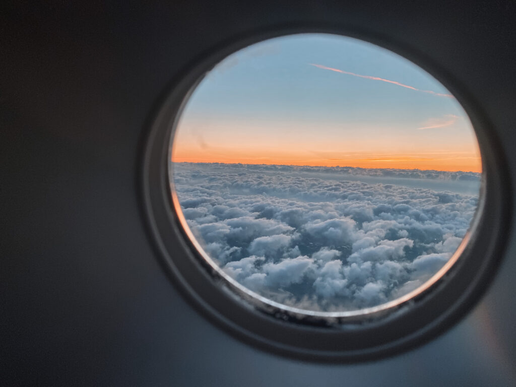 Flight attendant quotes: Sunset sky through an airplane exit door window 